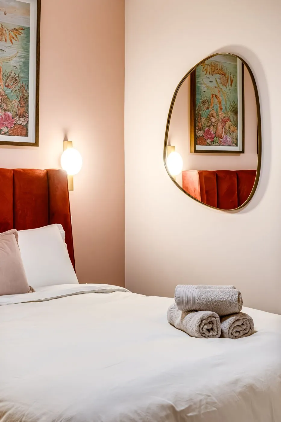 Bedroom with a red velvet headboard and blush walls