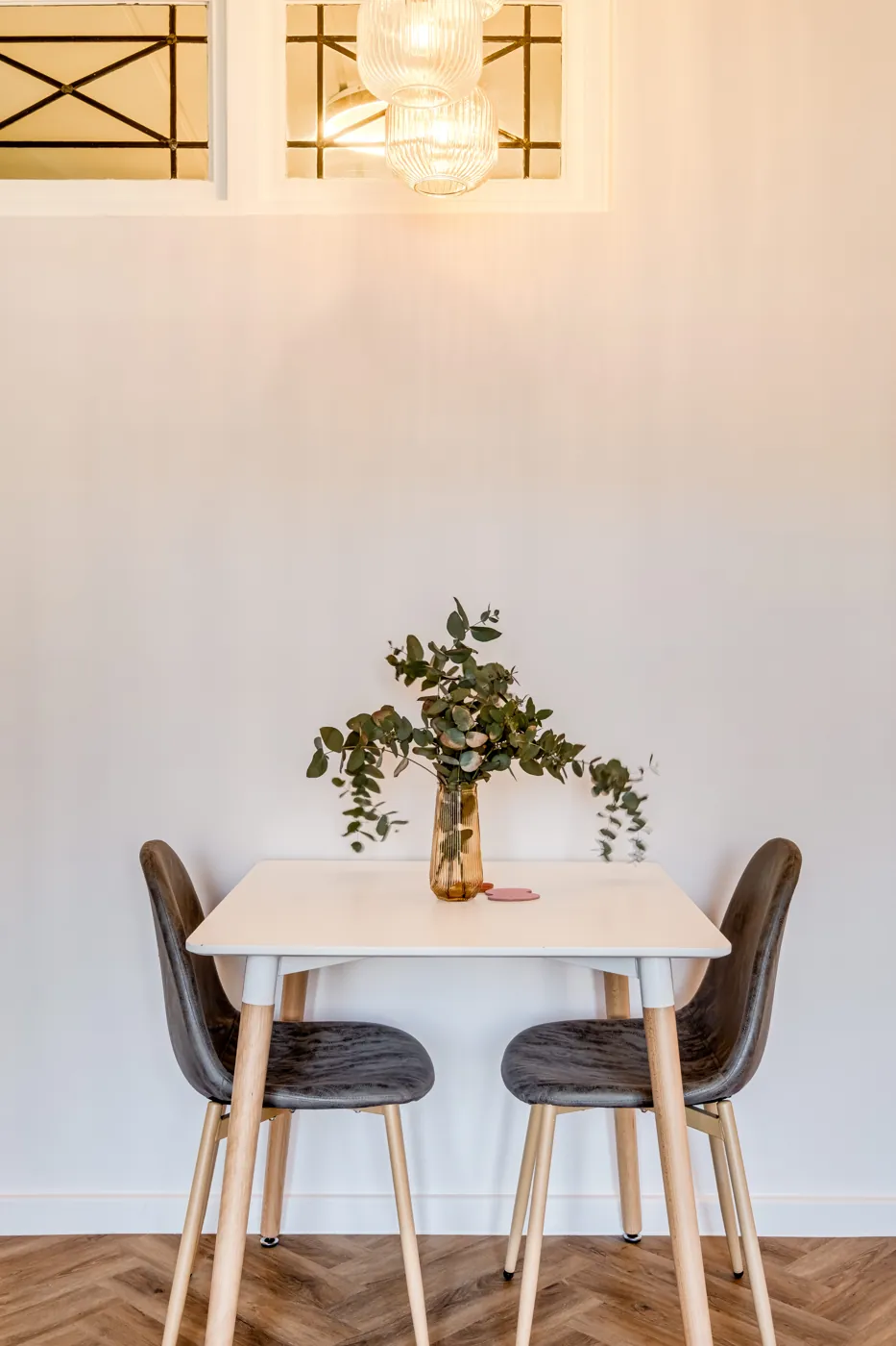 Dining table for two by the window, with eucalyptus in a vase
